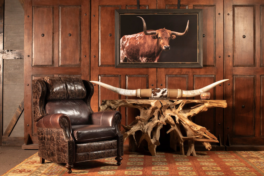 Western-style leather wingback chair with crocodile embossing, driftwood console, and mounted longhorn décor in a rustic lodge setting.