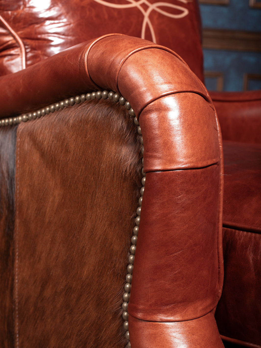 Side view showing the solid wood frame and hair-on-hide details of the Amarillo Red Stitch Accent Chair with matching ottoman.