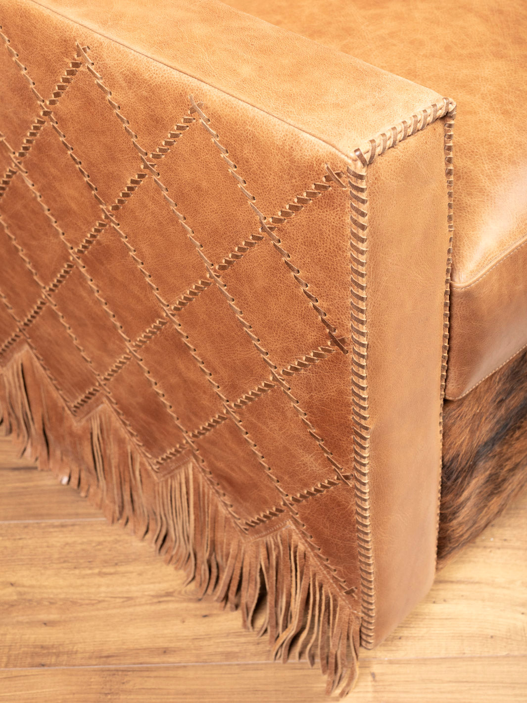 Side view showing diamond-stitched panels and fringe skirt on Western leather swivel chair