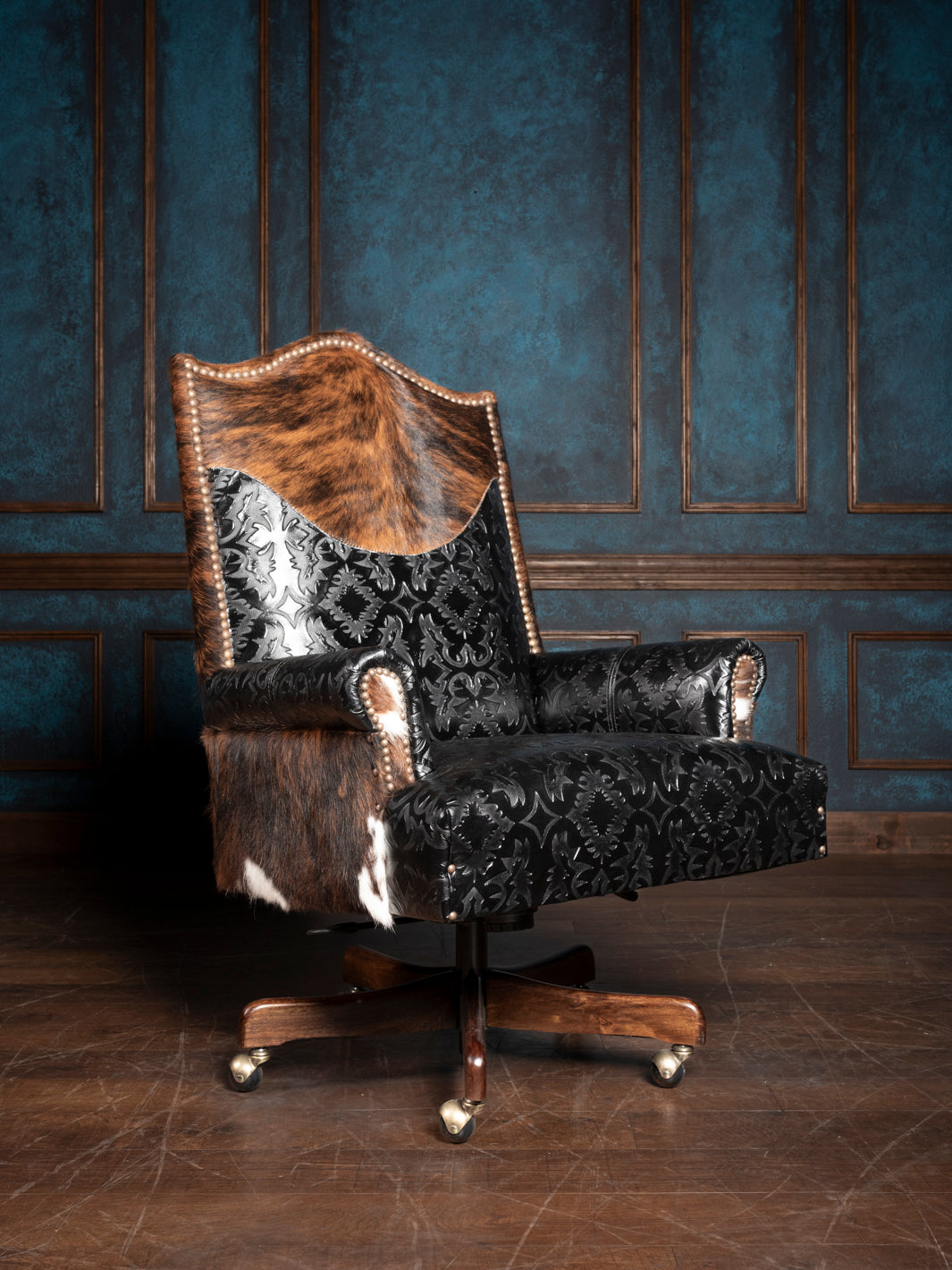 A luxurious leather desk chair with a combination of solid black and patterned black and silver fabric, featuring a wooden frame and metal accents.