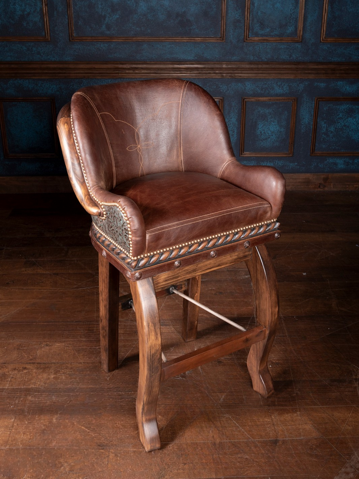 A hand-carved wooden bar stool with bronze leather upholstery, featuring a traditional design.