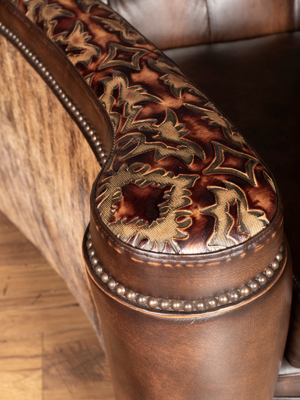 Close-up of upper arm: Hand-tooled leather accent on curved sofa arm with burnished finish