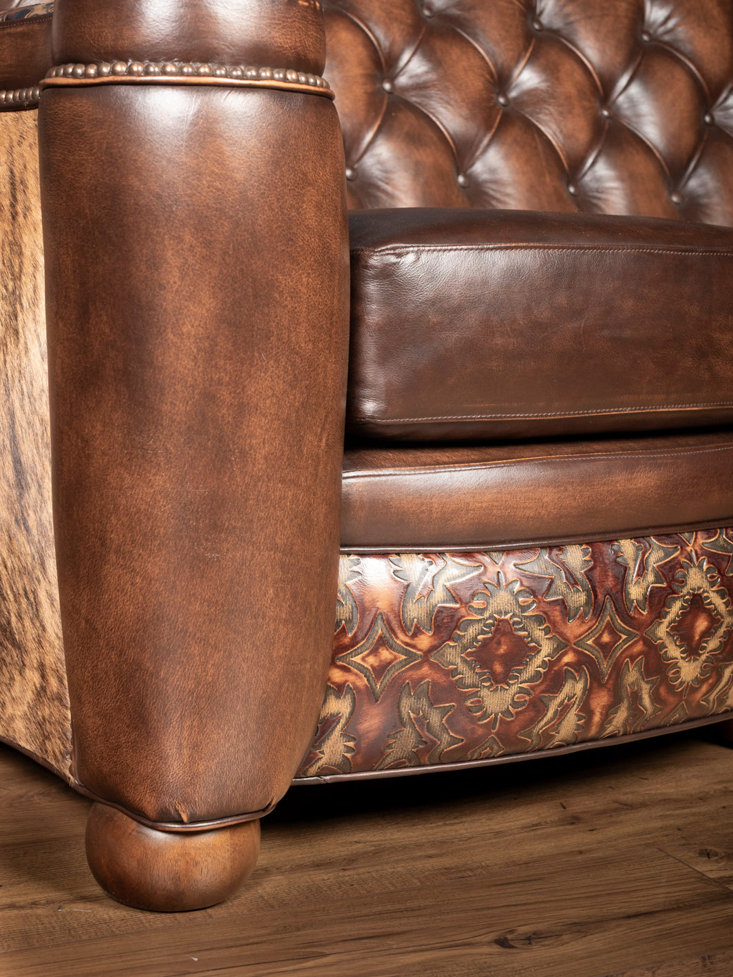 Close-up of seat and tooling: Embossed leather tooling on base with button tufted seat and burnished leather