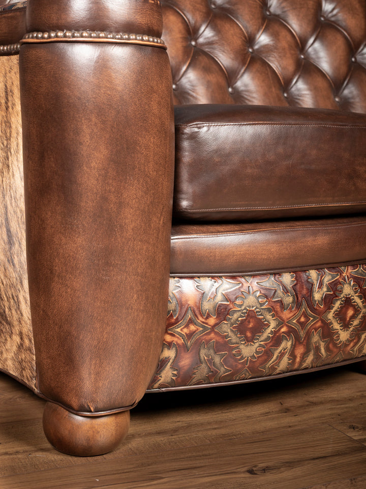 Close-up of seat and tooling: Embossed leather tooling on base with button tufted seat and burnished leather