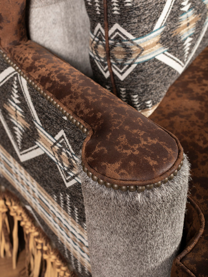 Armrest detail featuring nailhead trim, distressed leather, and tribal fabric