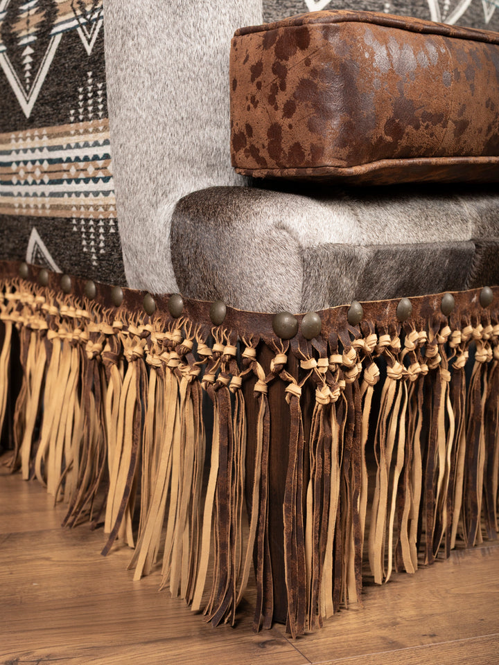 Close-up of leather fringe and cowhide upholstery detail at base of settee