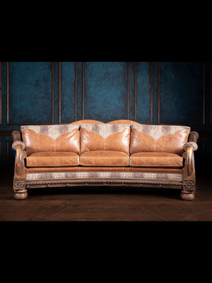 A caramel croc leather sofa with a hand-carved longhorn frame, set against a blue textured backdrop.