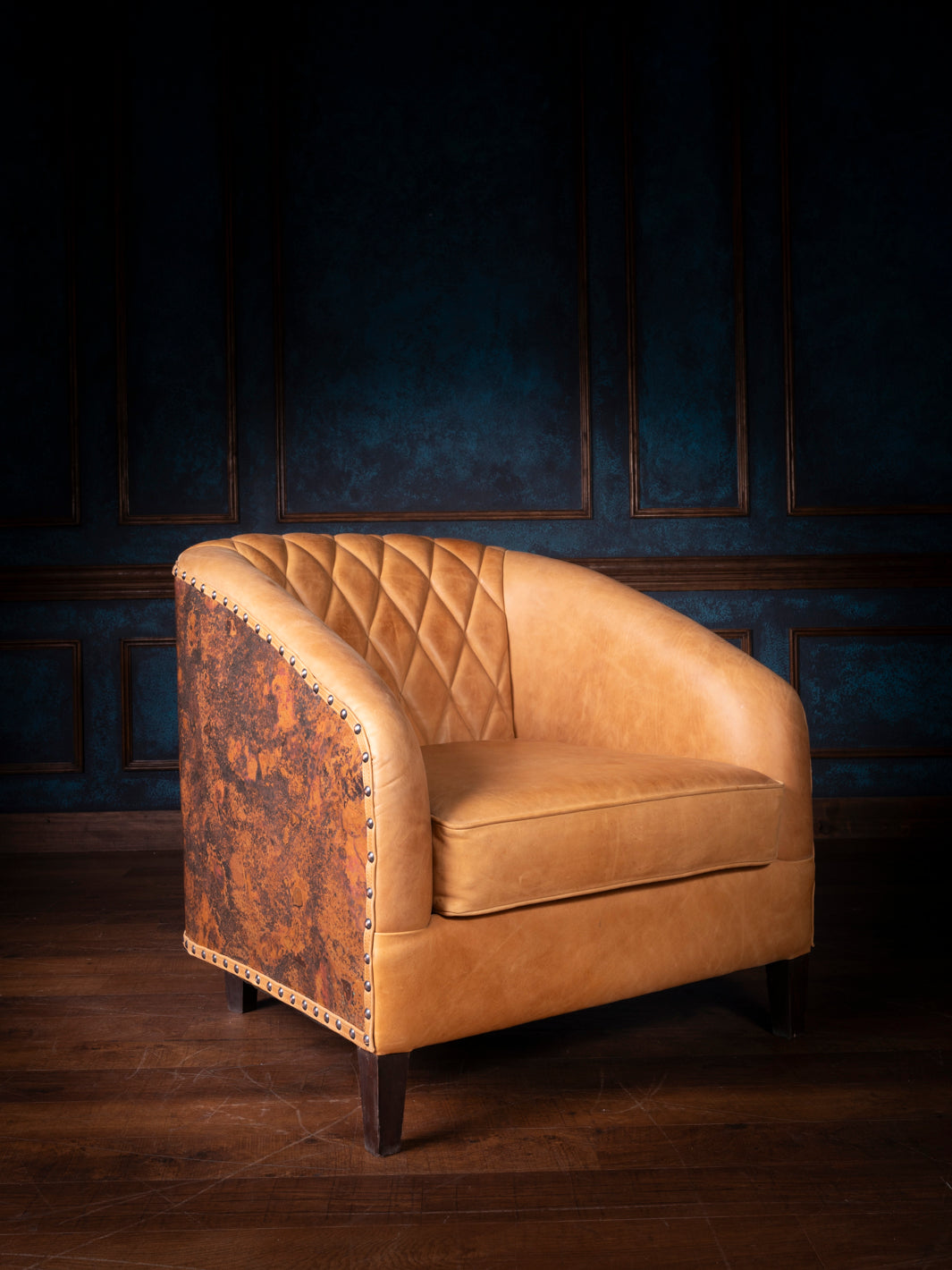 Front angle view of a Western leather accent chair with tan quilted leather, copper-toned side panels, and nailhead trim.