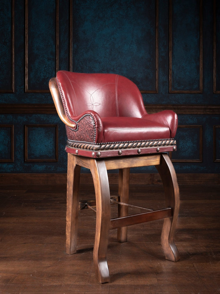A red leather bar stool with a wooden base, featuring detailed embossing and nailhead trim on a dark background.