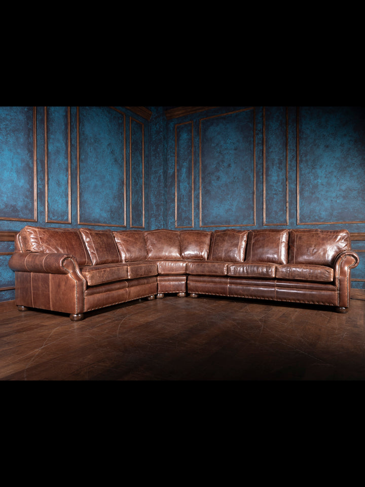 A large brown leather sectional sofa in a room with blue walls and wooden flooring.