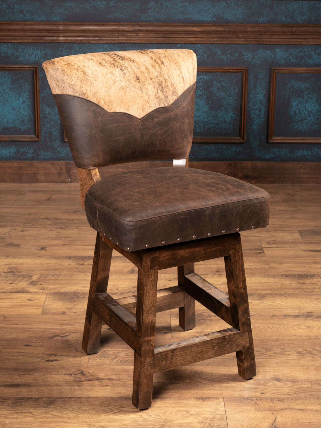 Angled Front View: Western swivel bar stool with sculpted cowhide and leather upholstery on wooden base