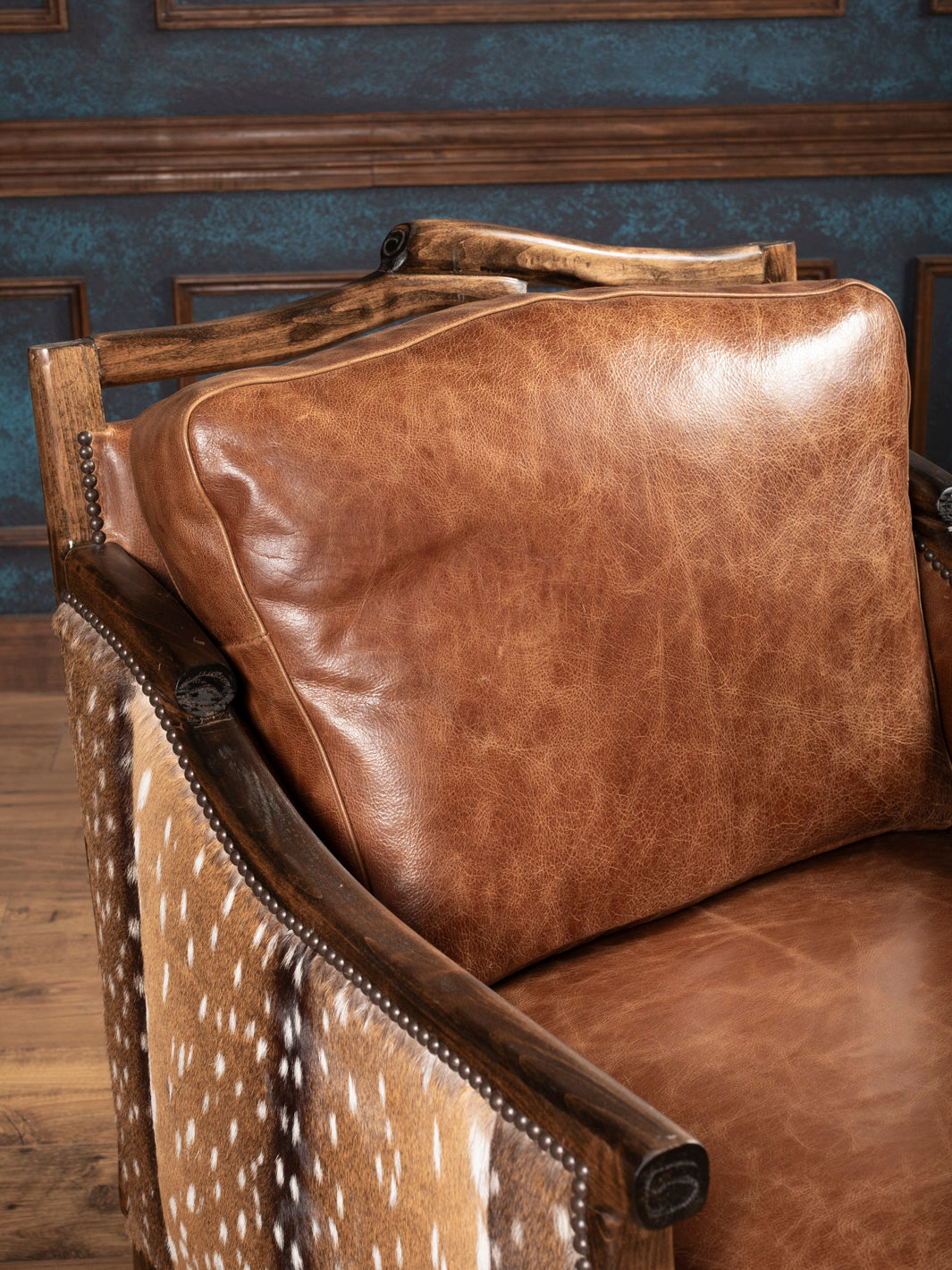 Top view of pillow-back leather cushion and sculpted wood arm on rustic armchair