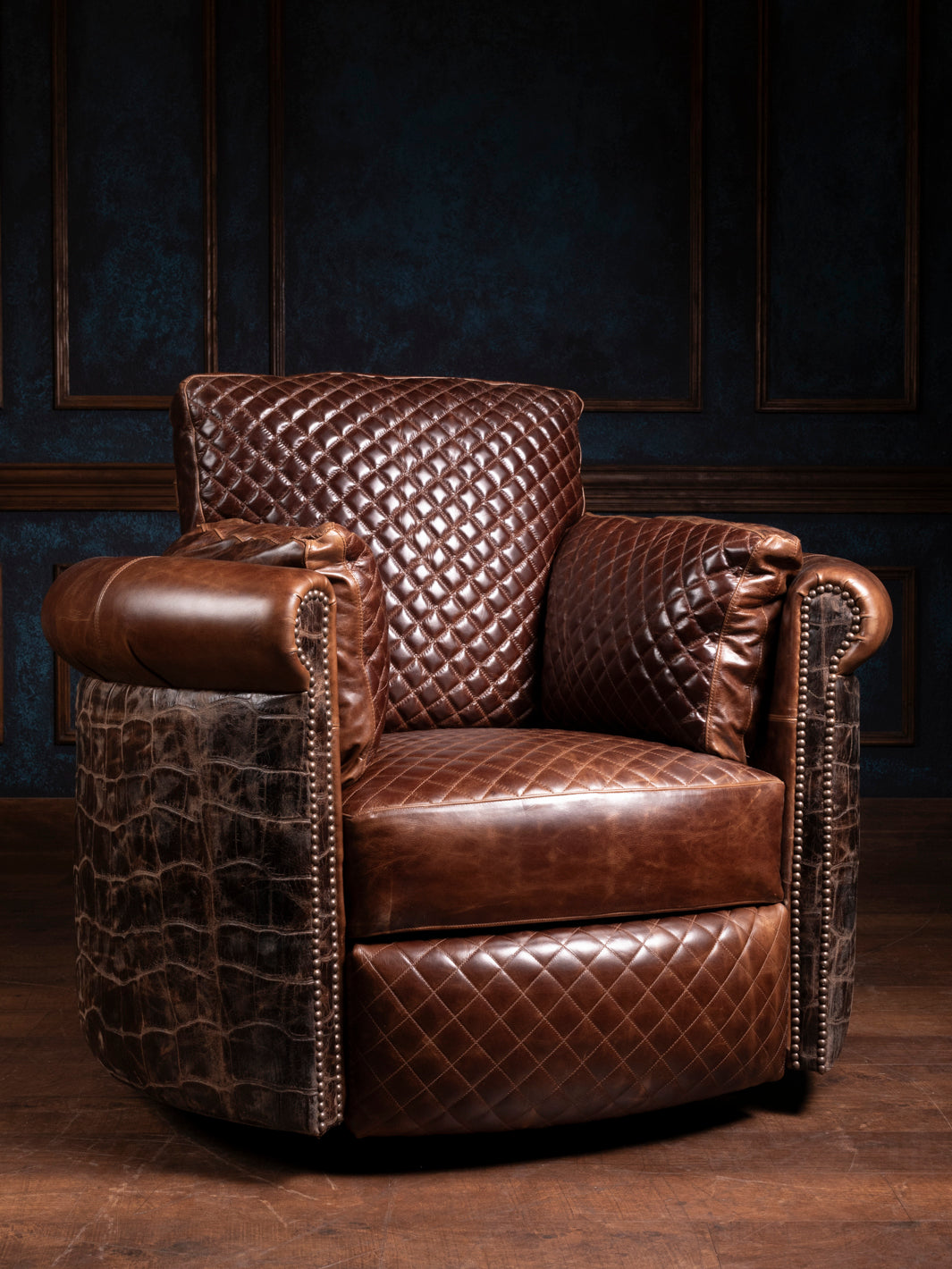 A brown crocodile leather swivel chair with diamond-quilted cushions, positioned against a dark, panelled wall.