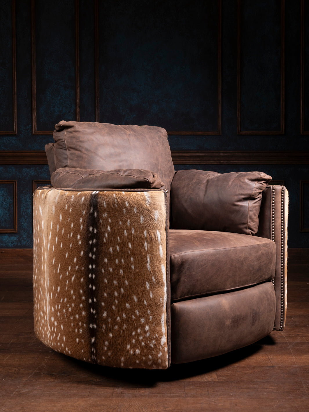 A brown leather axis snug swivel recliner chair with a patterned accent on the side, set against a dimly lit room.