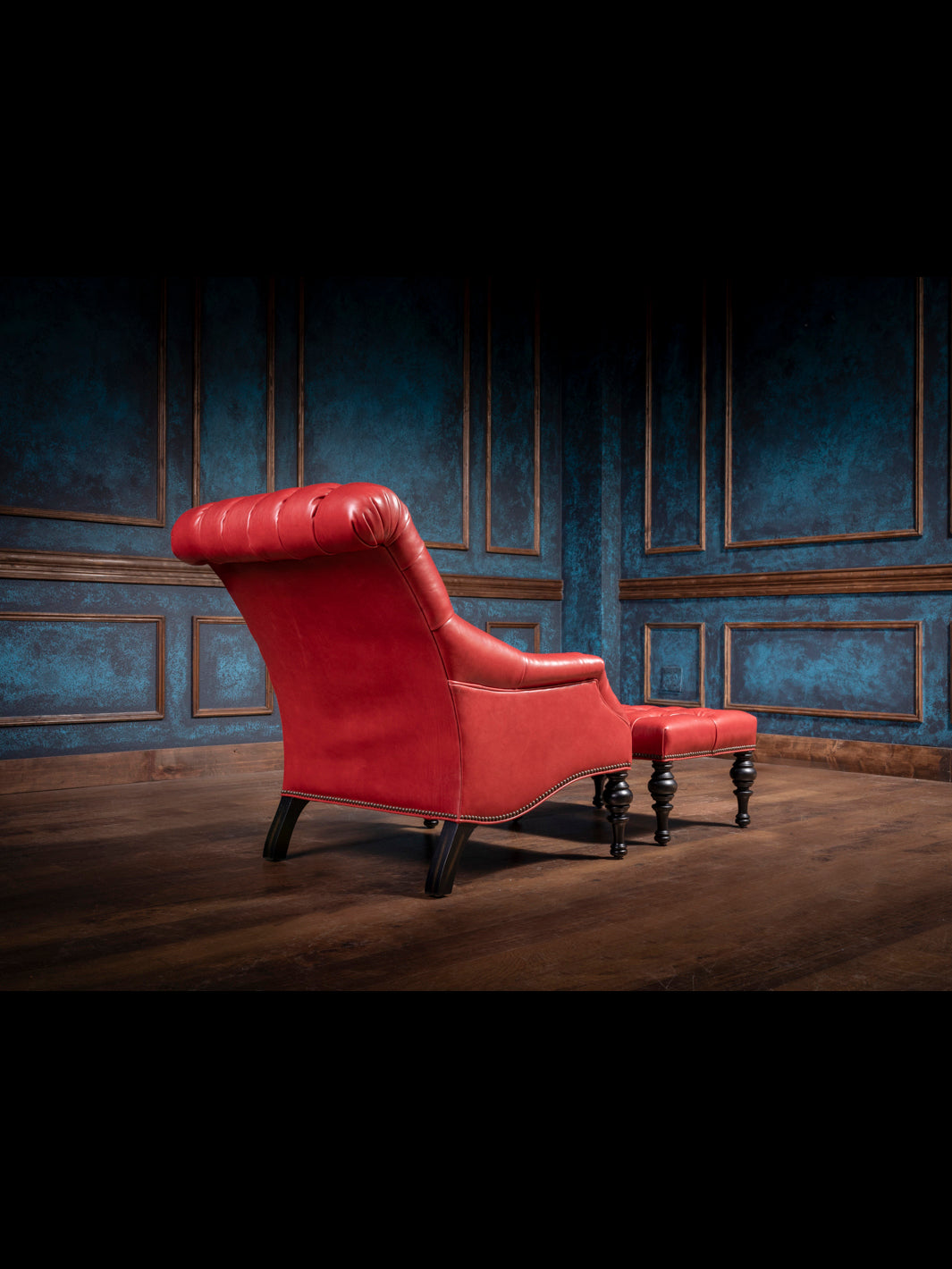 Handcrafted red leather accent chair with a matching tufted ottoman, featuring rolled backrest and curved wood legs in a Western-inspired luxury setting.