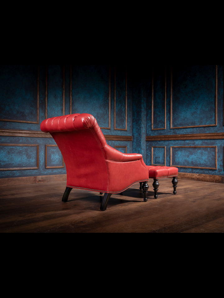 Handcrafted red leather accent chair with a matching tufted ottoman, featuring rolled backrest and curved wood legs in a Western-inspired luxury setting.