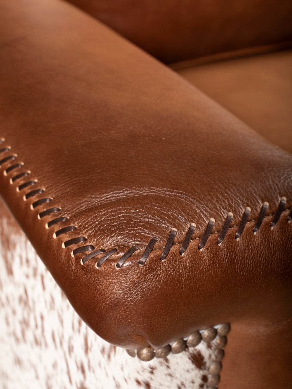 Close-up of brown leather armchair with visible stitching