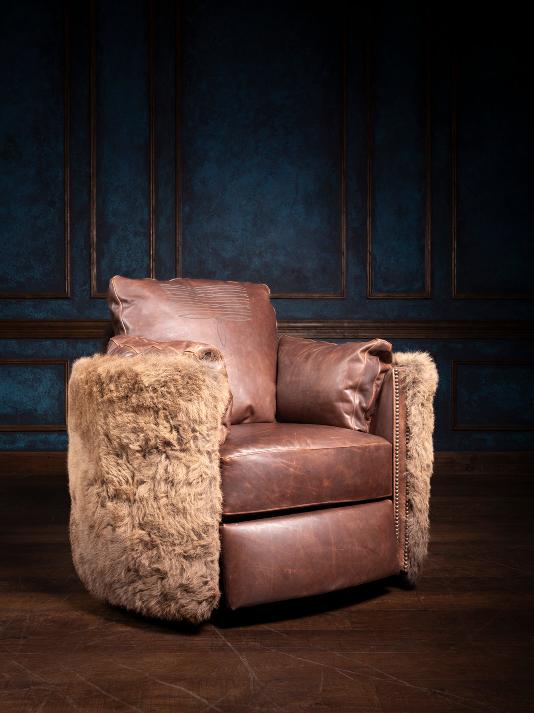 A brown leather recliner with plush cushions and buffalo hair on hide accents on the armrests, set against a blue backdrop.