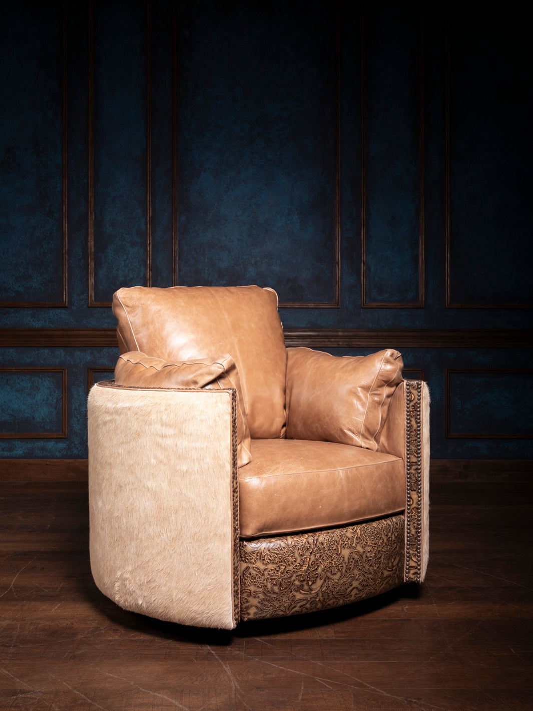 A brown leather swivel recliner chair with floral embossed details, positioned against a blue panelled wall.