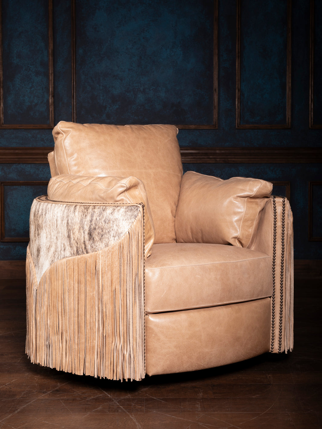 A beige leather recliner chair with fringe detailing on the arms, set against a dark paneled background.