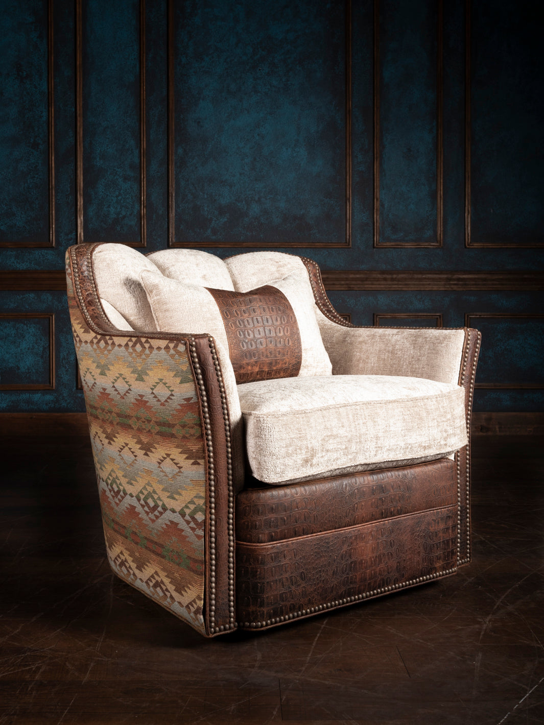 A luxurious Heritage Mesa Swivel Chair with a combination of floral upholstery and brown leather, positioned in a dimly lit room with panelled walls.