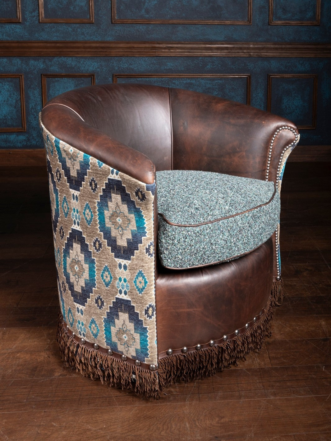 A swivel chair with a mix of brown leather and turquoise patterned fabric, featuring fringe details.