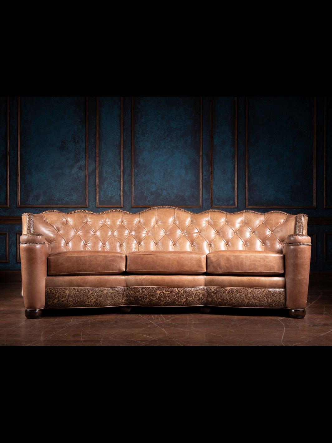 Full front view of a Western leather sofa with button-tufted back, tooled leather accents, and hair-on-hide sides.