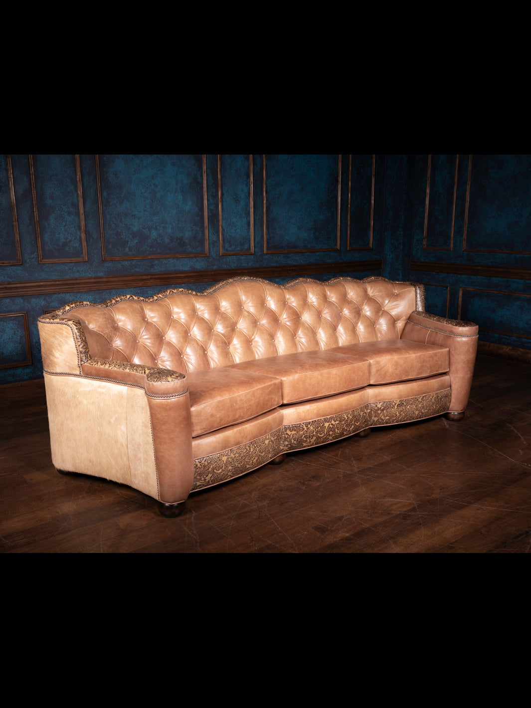 Three-quarter view of the Western leather sofa with sunflower tooling, rich tan leather, and textured hide panels.