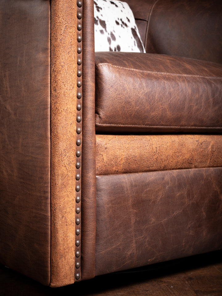 Detailed view of the armrest on Bison Ridge leather chair, featuring premium nailhead detailing and a textured leather finish.