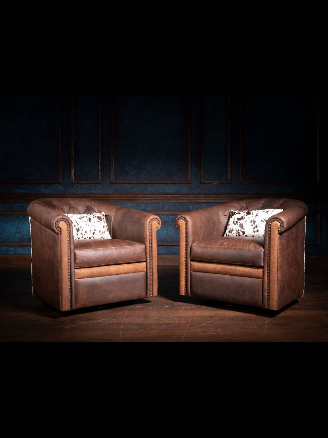 Two Bison Ridge leather chairs in a refined setting with dark blue wall paneling, highlighting their luxurious design and craftsmanship.