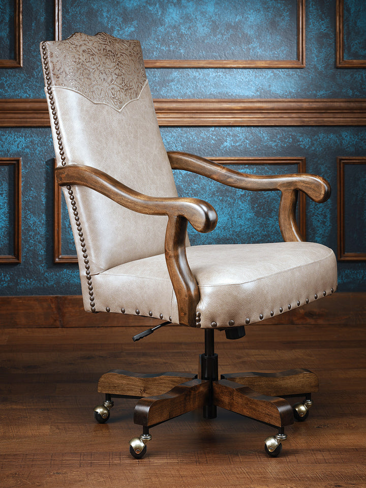 A classic cowgirl desk chair with a beige upholstered backrest and seat, featuring a wooden frame and embossed leather details, mounted on a five-star base with caster wheels.