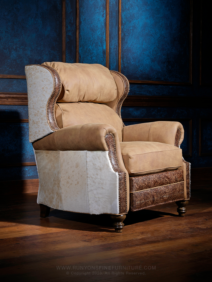 A Southwest Blonde Leather Recliner with floral brown embossed accents, upholstered in a cream color, positioned in a room with a blue wall and wooden flooring.