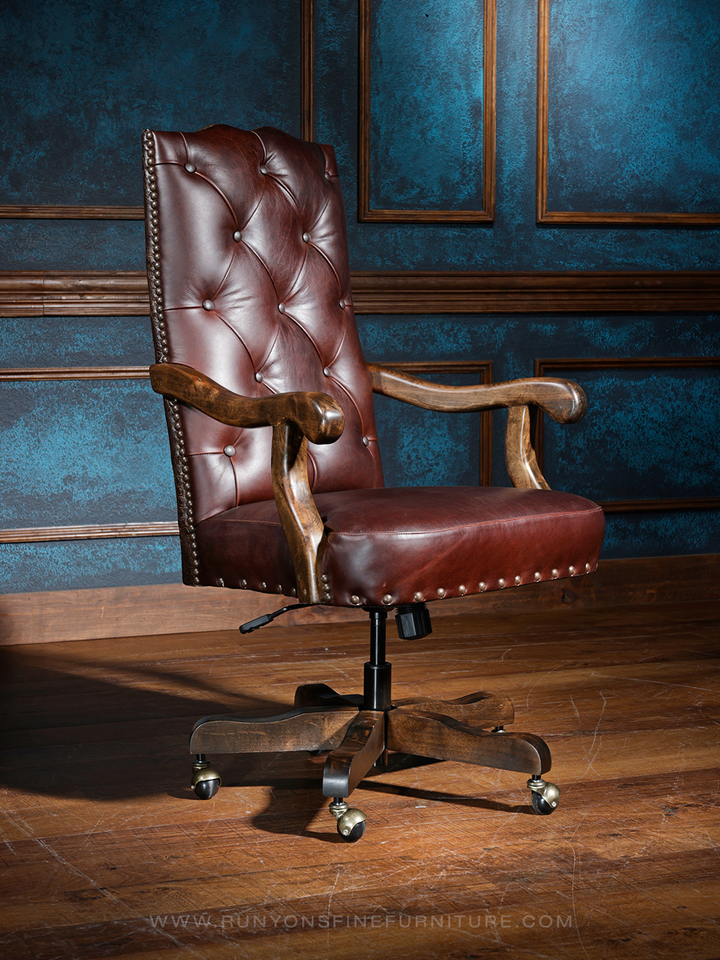 A brown, tufted, leather desk chair with a crocodile embossed pattern, featuring wooden armrests and a dark brown backrest, set against a blue background.