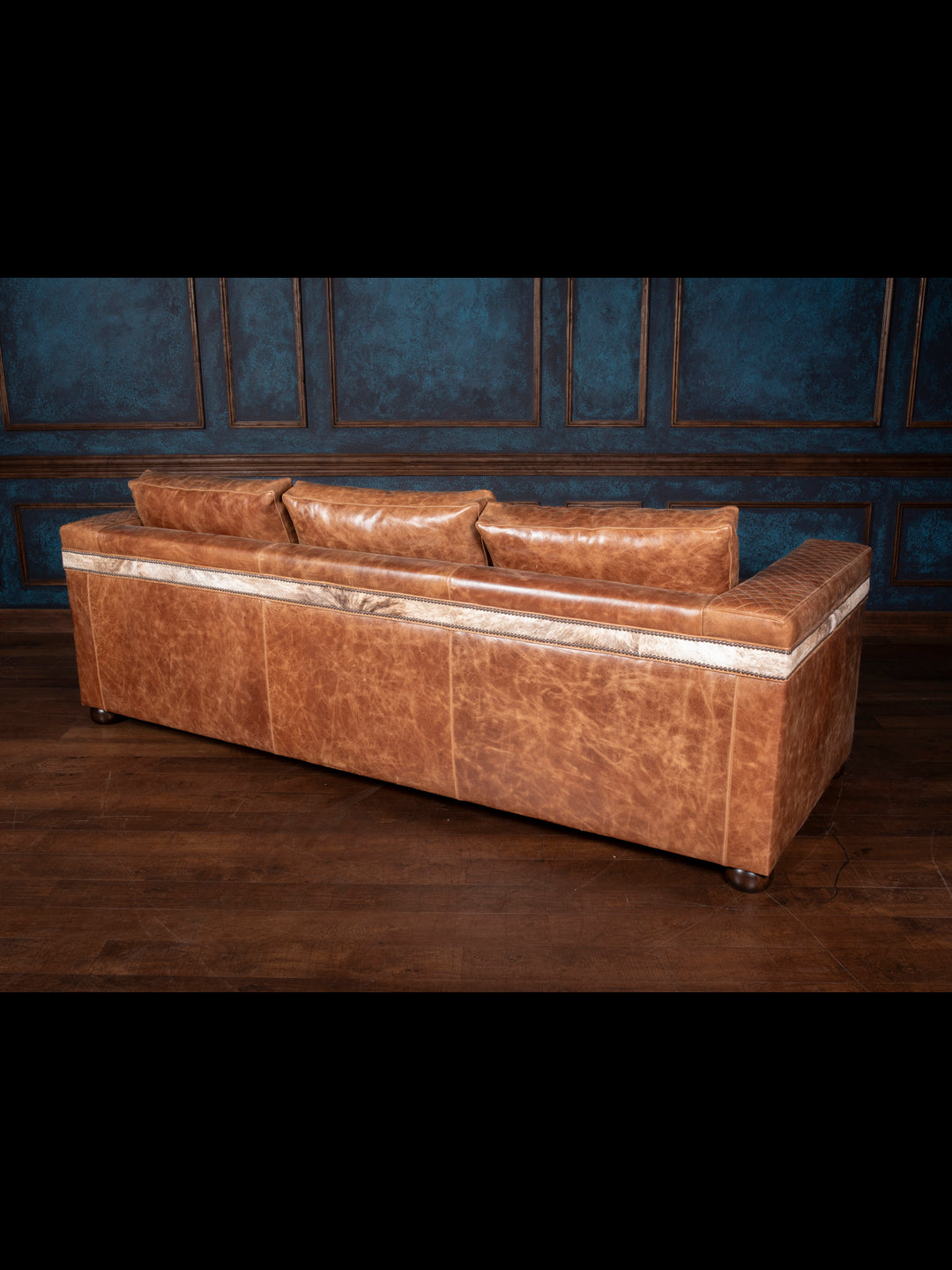 Desert Luxe Leather Architect Sofa, featuring premium quilted leather and hair-on-hide accents, showcased in a stylish room setting on a wooden floor.