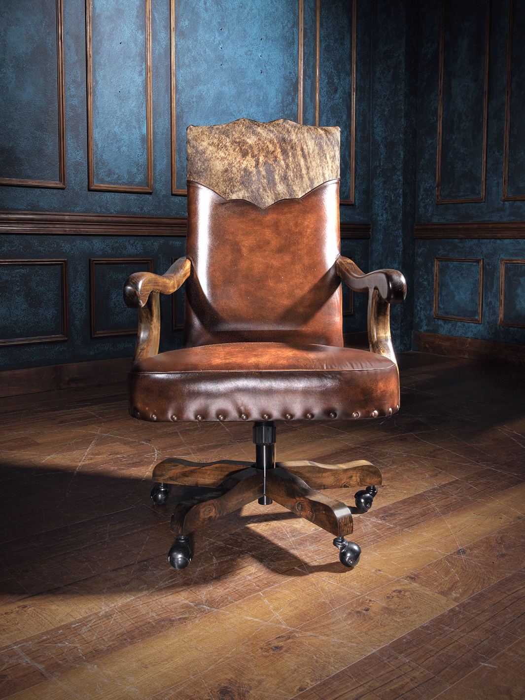 A brown leather desk chair with a classic design, featuring armrests and a caster base, positioned in a room with wooden paneling.
