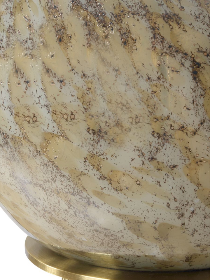 Close-up detail of a glass lamp base with swirling beige, brown, and cream-colored patterns, resembling natural stone or marble textures, mounted on a brass base