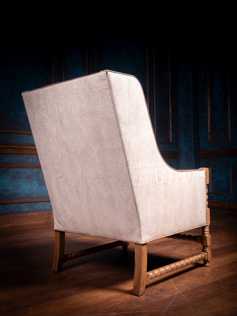 Back view of a Western-style accent chair with creamy textured faux reptile panels and a gracefully curved silhouette, supported by carved wood legs.