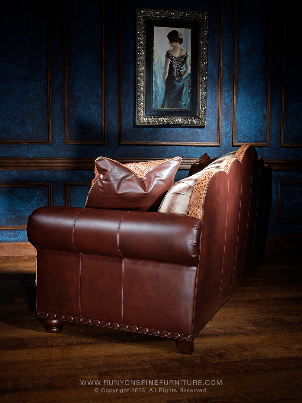 side angle of a rich brown leather sofa with curved arms and vertical seam details, accented by crocodile-embossed leather and soft leather throw pillows.
