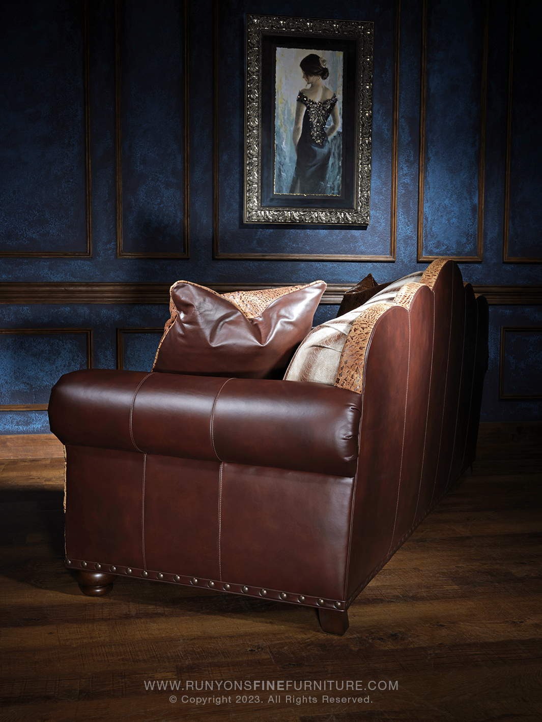 side angle of a rich brown leather sofa with curved arms and vertical seam details, accented by crocodile-embossed leather and soft leather throw pillows.