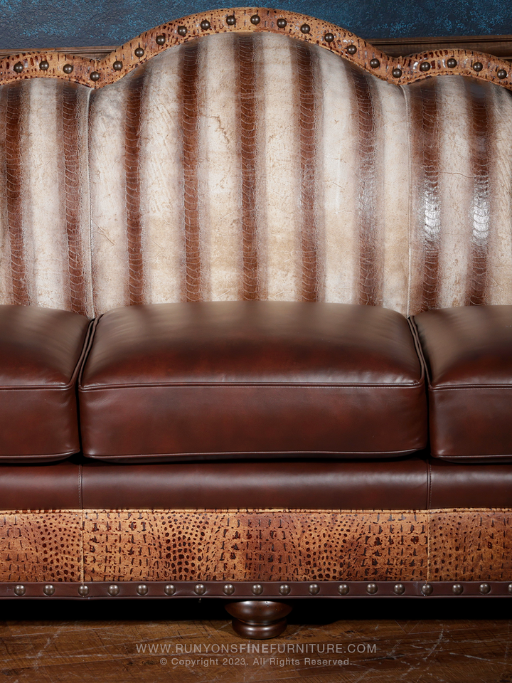 Close-up view of a luxury western-style leather sofa featuring vertical ridges of exotic leather on the backrest, with dark brown seat cushions and embossed leather trim on the base.