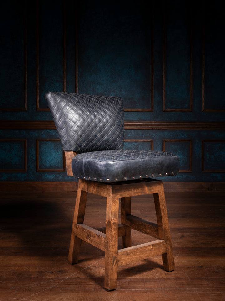 A navy blue leather bar stool with diamond stitching and a rustic wooden base, displayed in a dimly lit room.