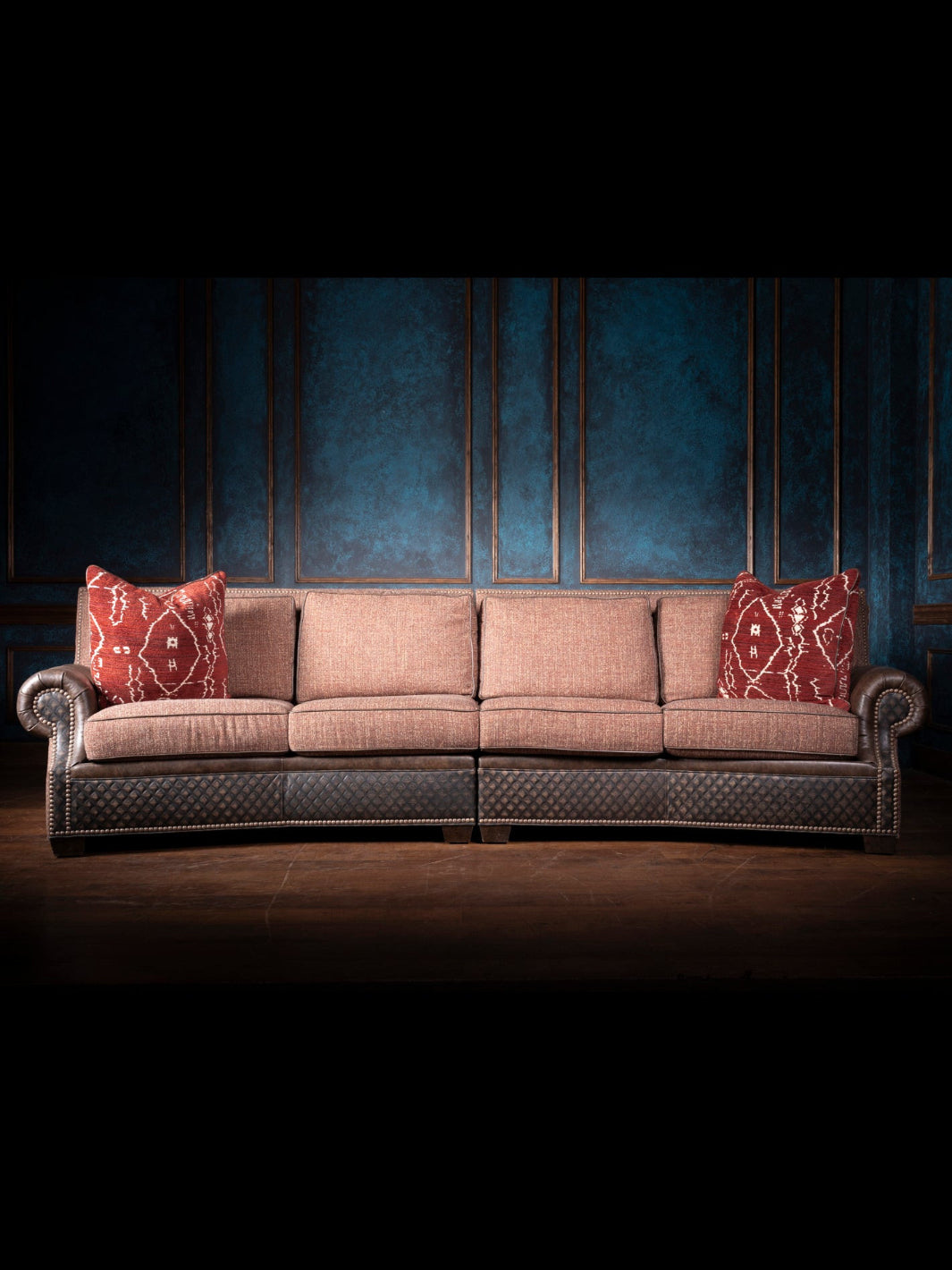 Brown sofa with red patterned cushions against a dark background