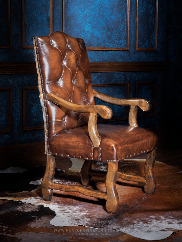 A brown leather dining chair with an axis back accent and deep button tufted seat back, featuring wooden legs and armrests.