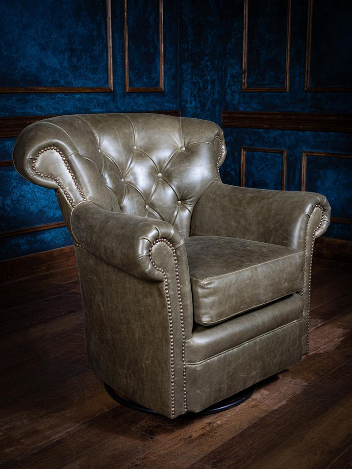 A dark green leather Chesterfield swivel chair with tufted backrest and nailhead trim, placed against a blue panelled wall.