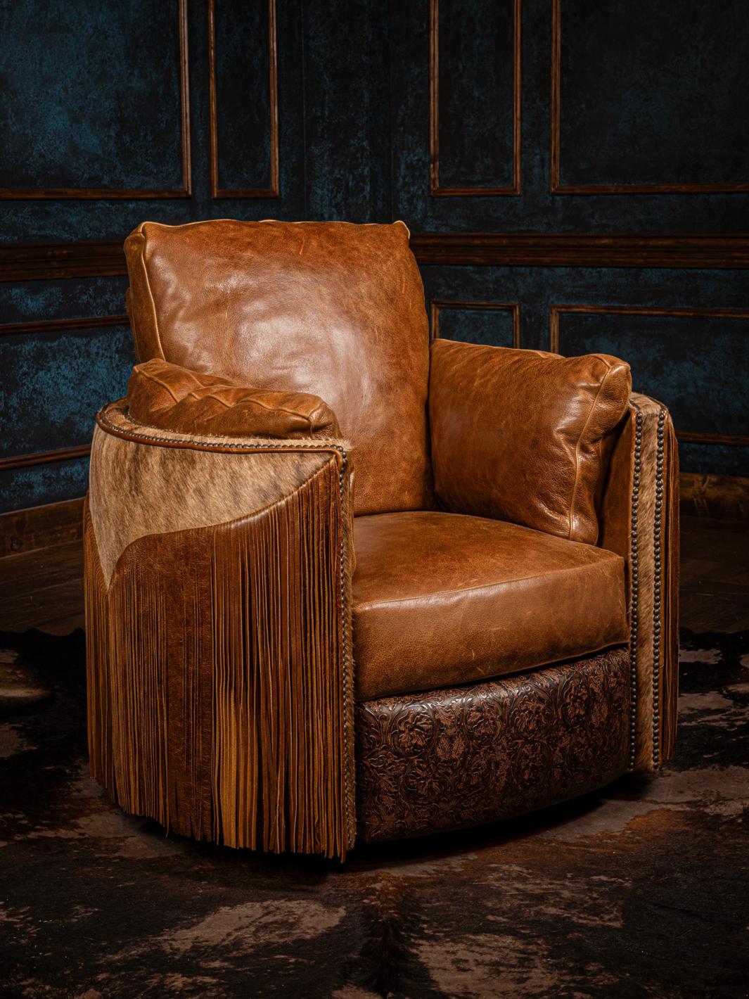 A brown leather swivel recliner chair with fringe detailing on the arms, set against a dark paneled background.