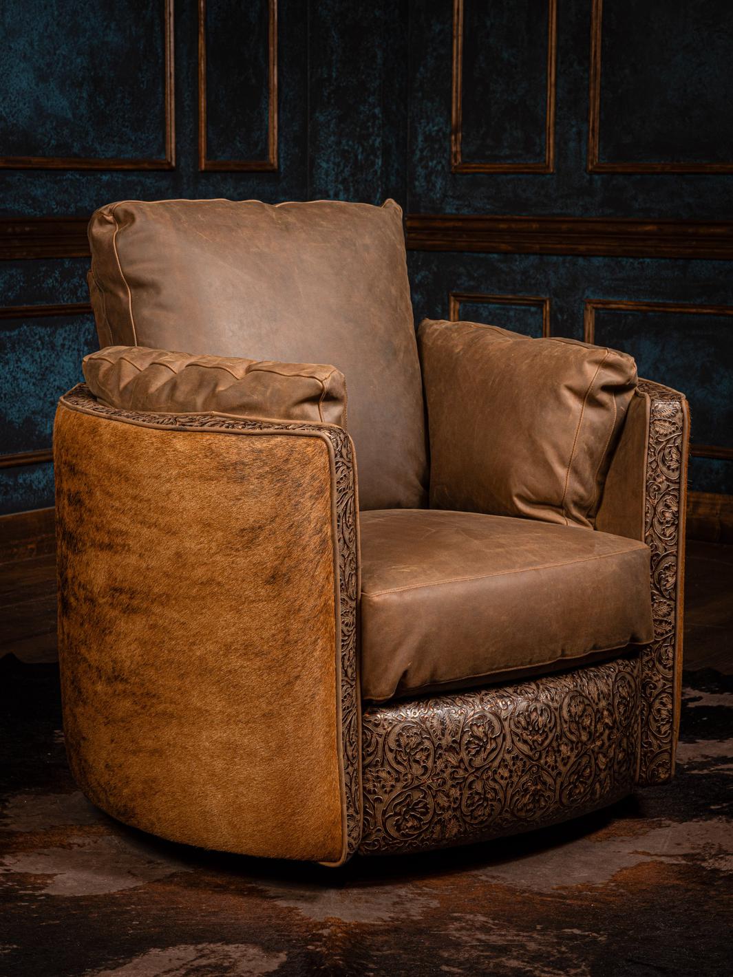 A tan leather snug swivel recliner chair with detailed embossing, positioned in a rustic setting.