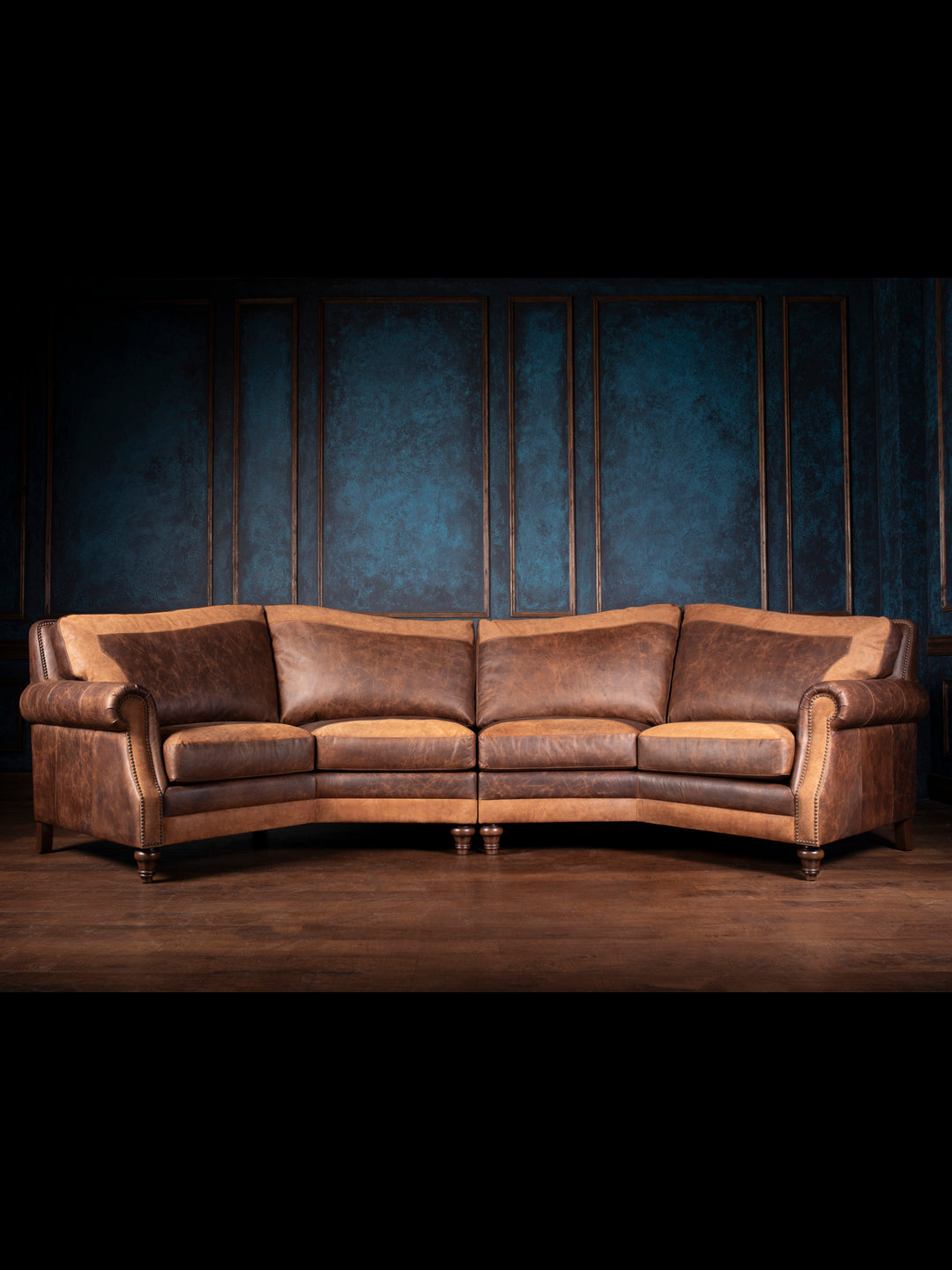 A brown leather sectional sofa with an L-shape design, displayed in a room with blue walls.