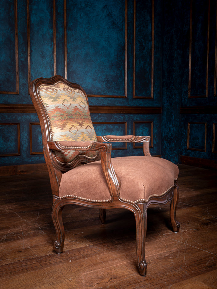Full view of the Southwestern Heritage Carved Chair, showcasing intricate wood carvings and a Southwestern-patterned fabric backrest, paired with a luxurious leather seat.