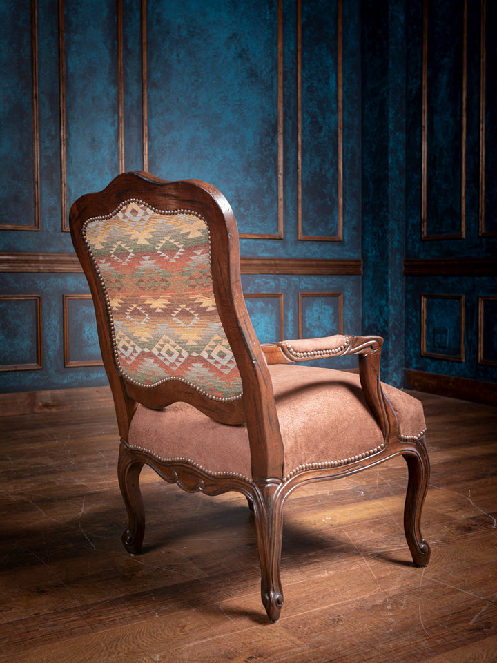 Back view of the Southwestern Heritage Carved Chair, highlighting the intricate wood carvings on the backrest and the Southwestern-patterned fabric, showcasing the detailed craftsmanship and unique design