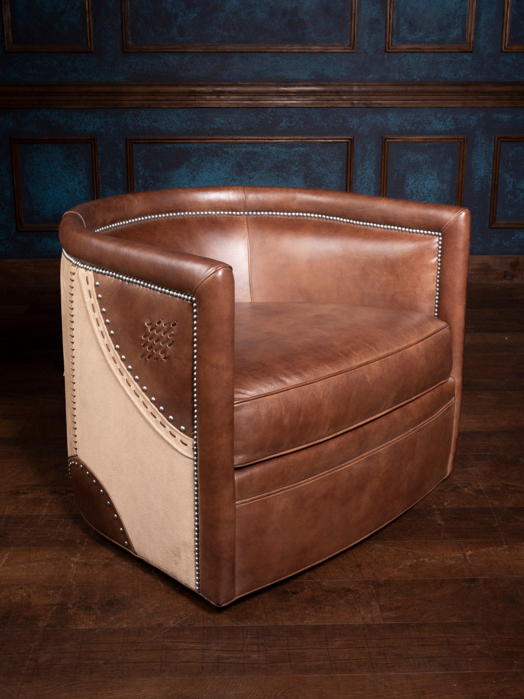 A brown leather swivel chair with stud stitch detailing and a rolled top, set against a dark background.